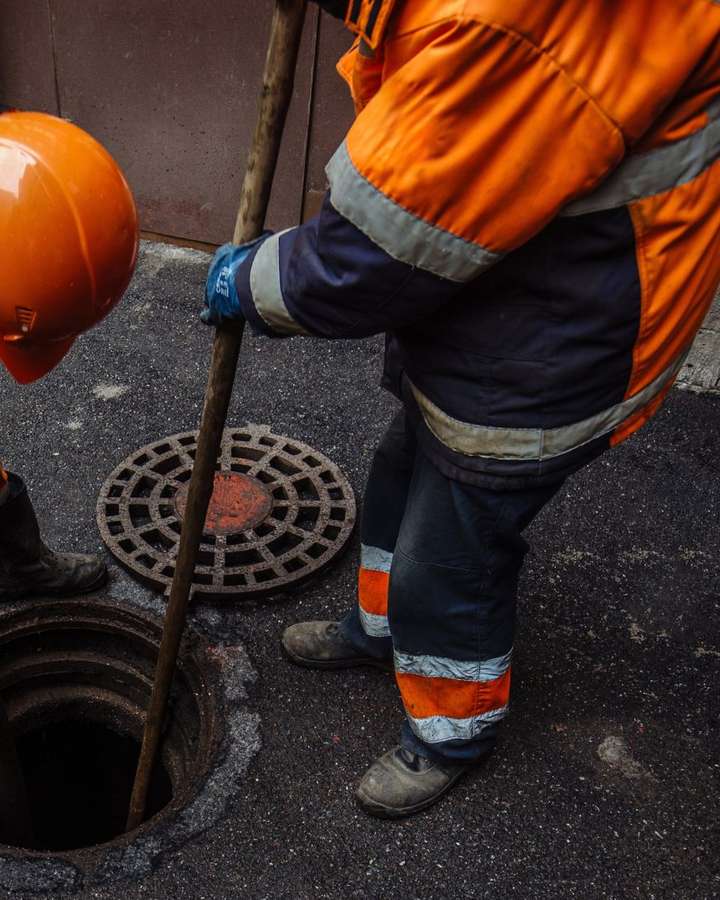 Técnico desentupindo rede de esgoto pelo bueiro em Curitiba