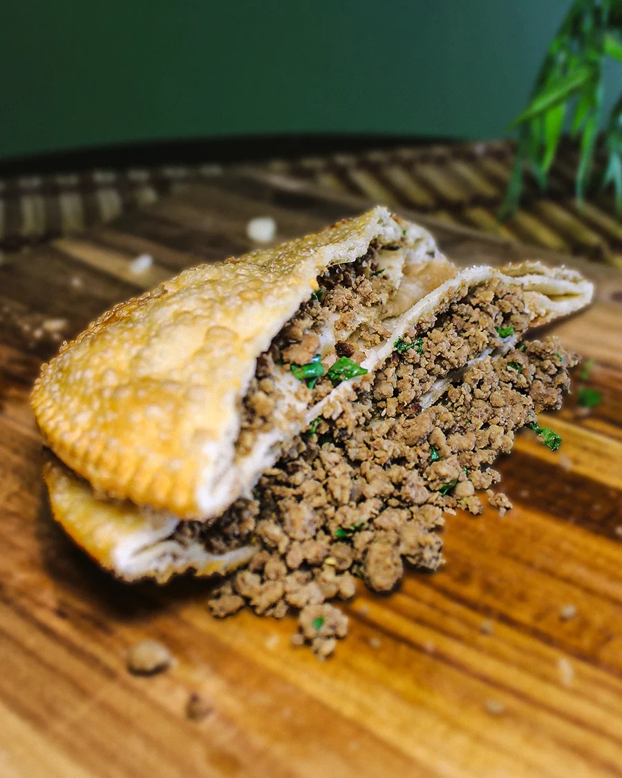 Pastel Carne aberto, mostrando o recheio, servido na Pastello