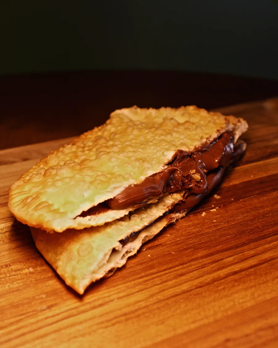 Pastel Chocolate Preto aberto, mostrando o recheio, servido na Pastello