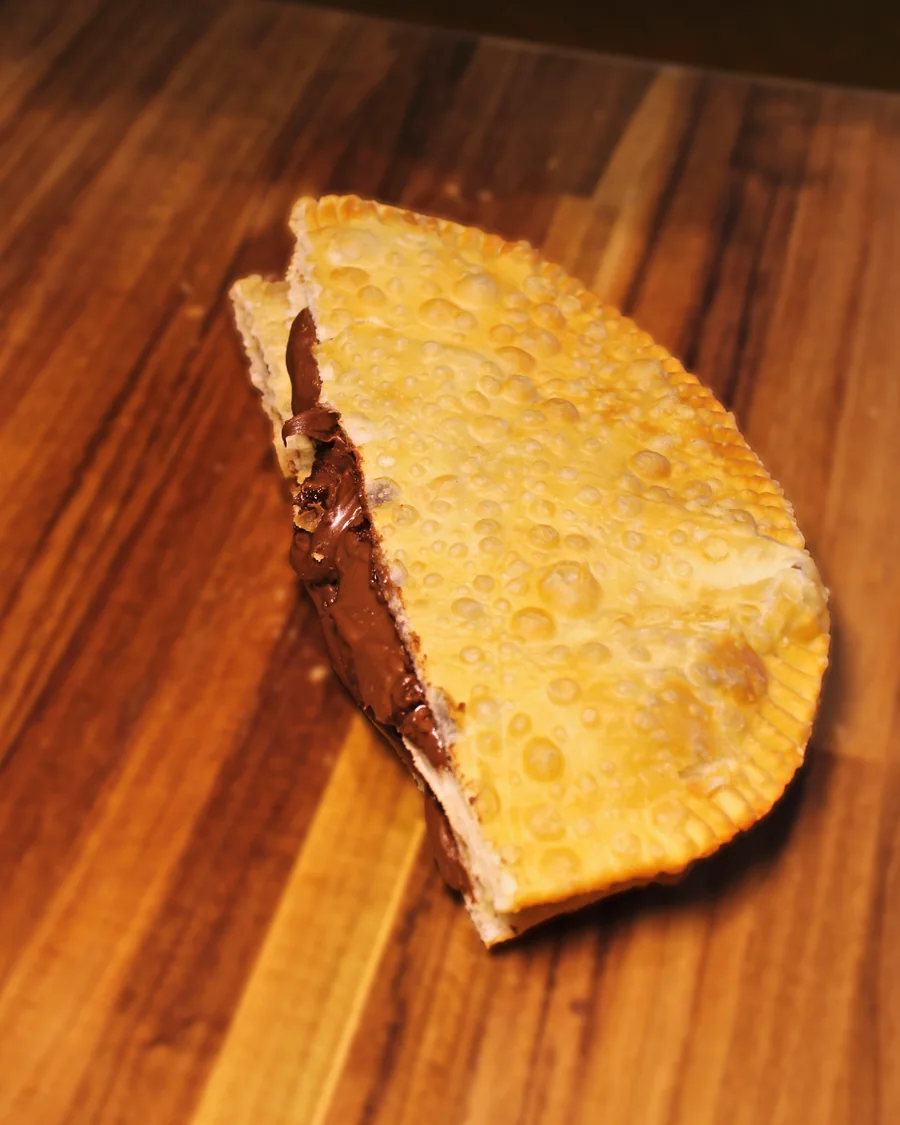 Pastel Creme de Avelã aberto, mostrando o recheio, servido na Pastello