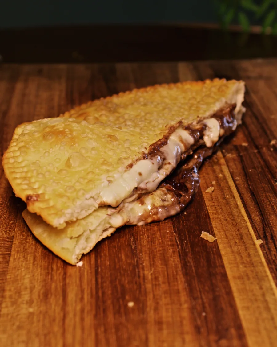 Pastel Dois Amores aberto, mostrando o recheio, servido na Pastello