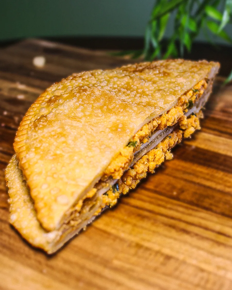 Pastel Frango aberto, mostrando o recheio, servido na Pastello