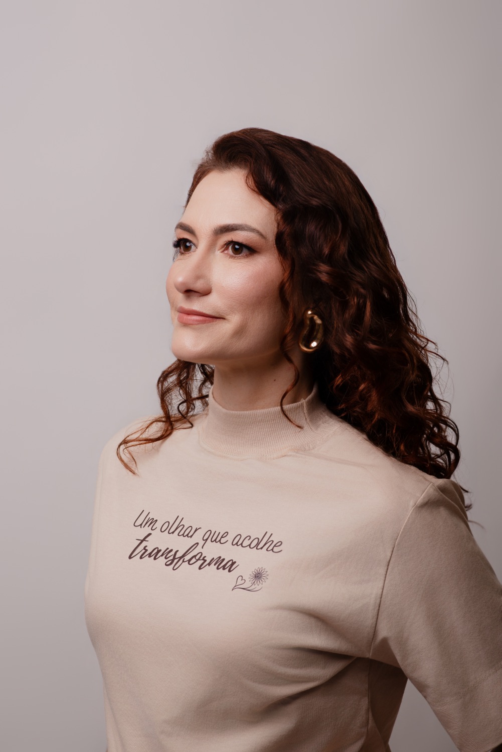 Scheilamar de perfil, usando a camiseta com a frase Um olhar que acolhe transforma